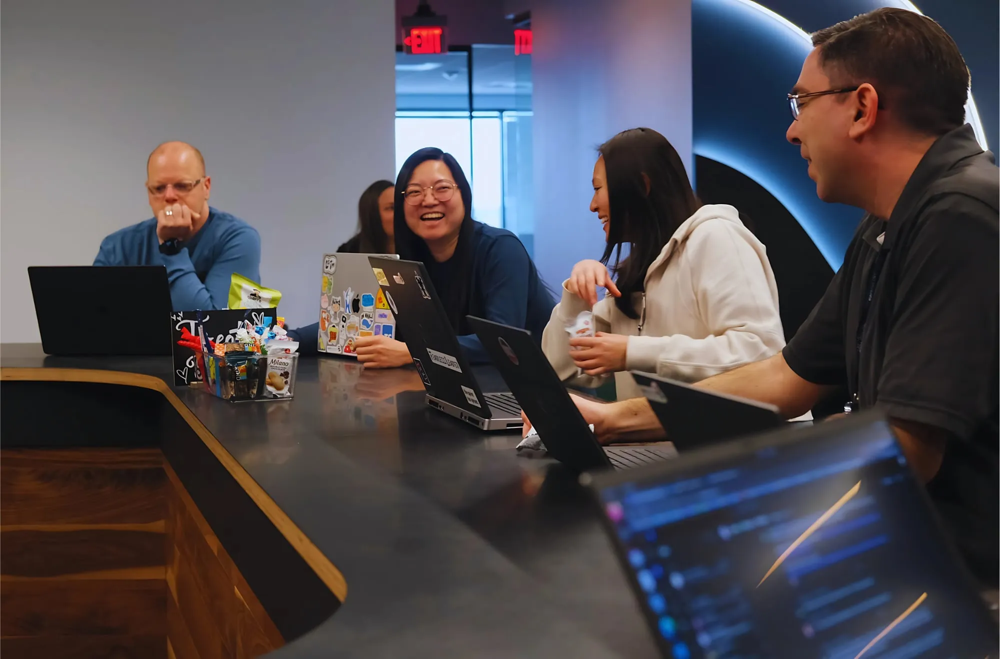 Engineers working together over laptops around a table in EXP's Herndon office.